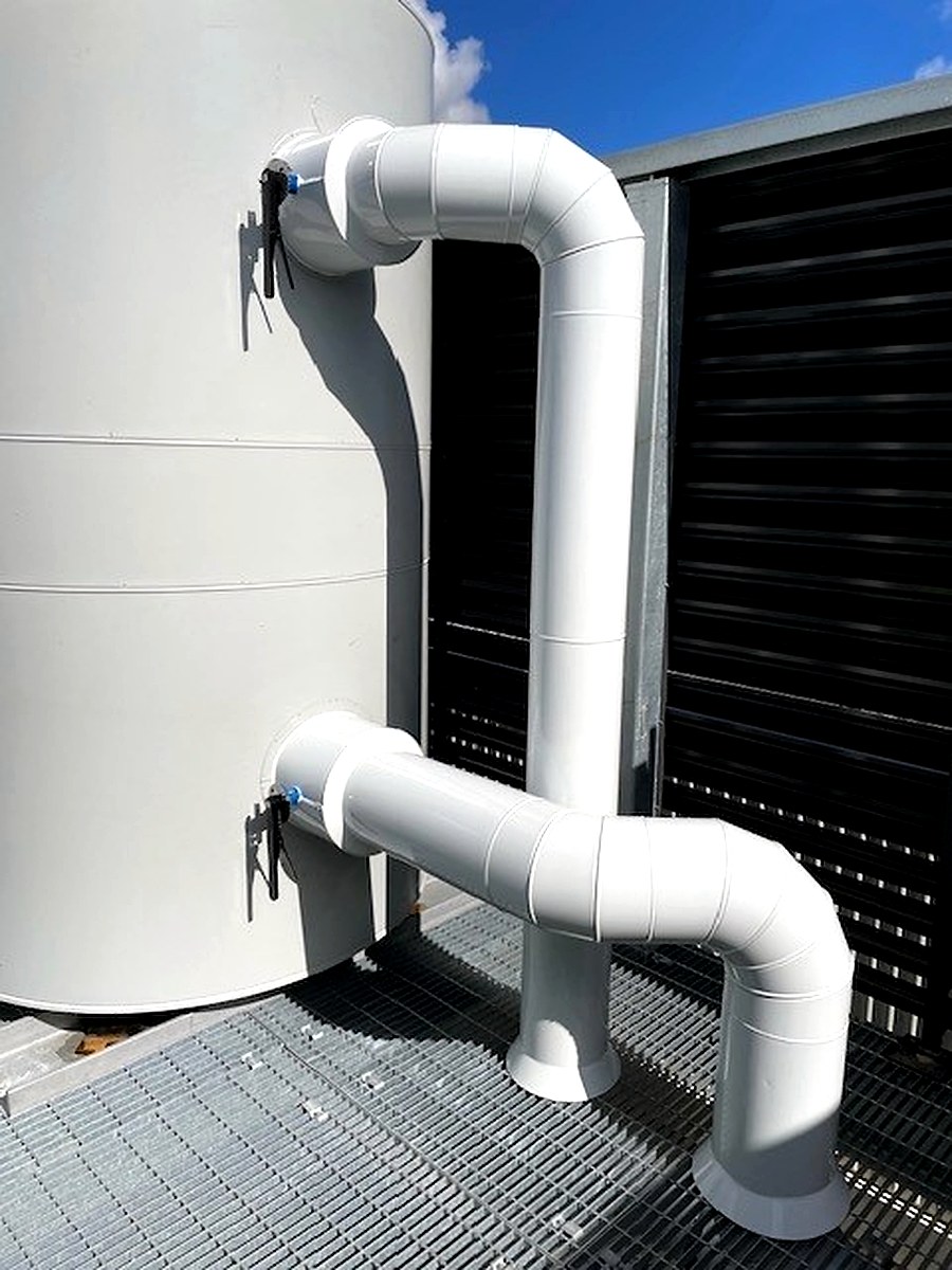White sheet metal clad pipe bend detail on a rooftop outdoor mechanical installation